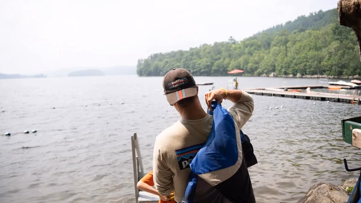 A camp waterfront specialist putting on a life jacket by the lake
